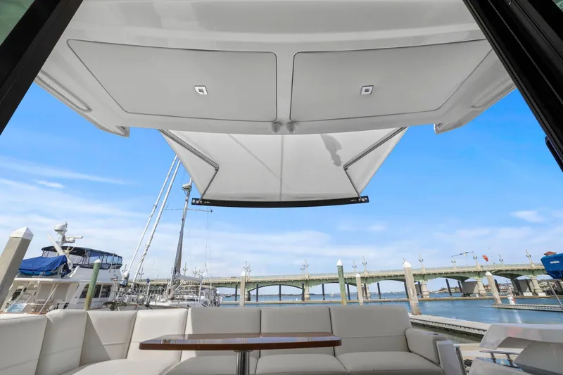 Slide: The Image of 2023 Tiara Yachts C49 Coupe with open canopy, docked near a scenic bridge. - 27