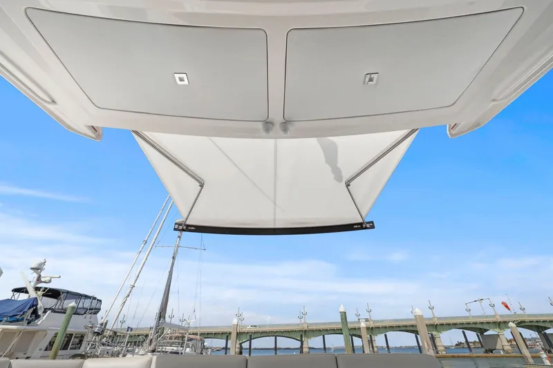 Slide: The Image of 2023 Tiara Yachts C49 Coupe with extended sunshade, docked near a bridge. - 28