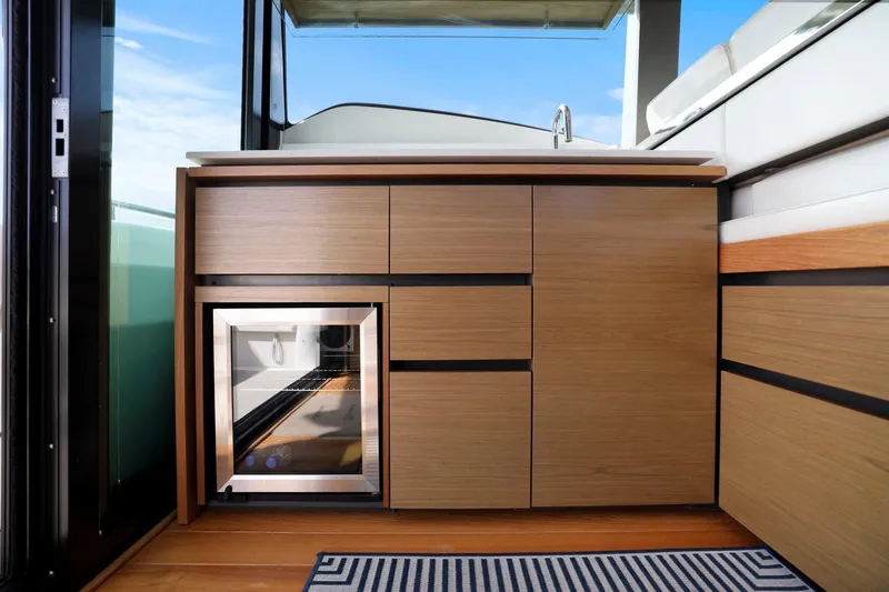 Slide: The Image of 2023 Tiara Yachts C49 Coupe interior with sleek wooden cabinetry and mini fridge. - 49
