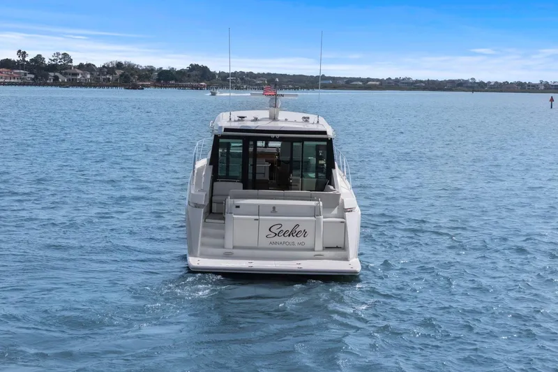 Slide: The Image of 2023 Tiara Yachts C49 Coupe cruising on a serene blue waterway. - 8