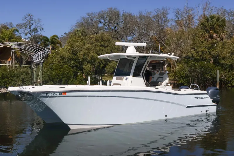 The Image of 2022 World Cat 280 CC-X boat on calm water, surrounded by lush greenery. - 0