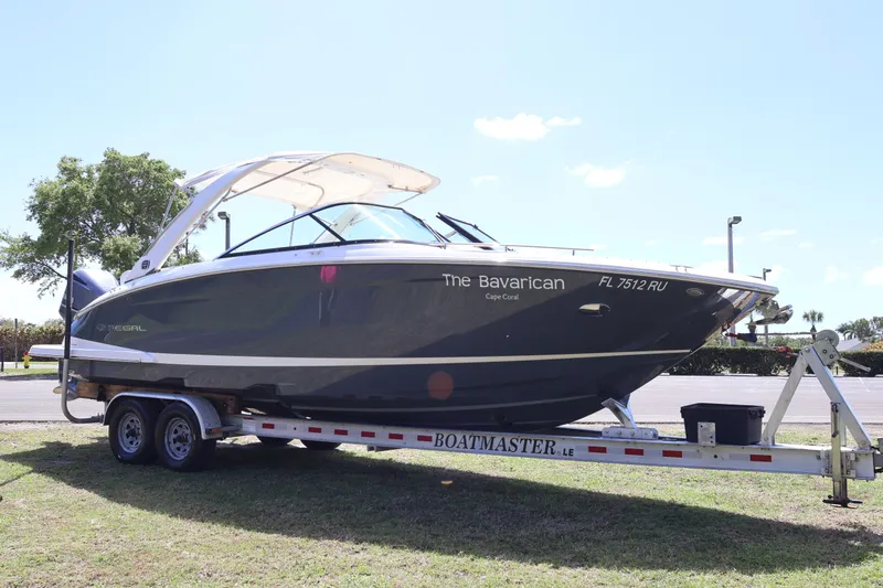 The Image of 2019 Regal 29 OBX boat on trailer, labeled "The Bavarican," parked outdoors. - 0