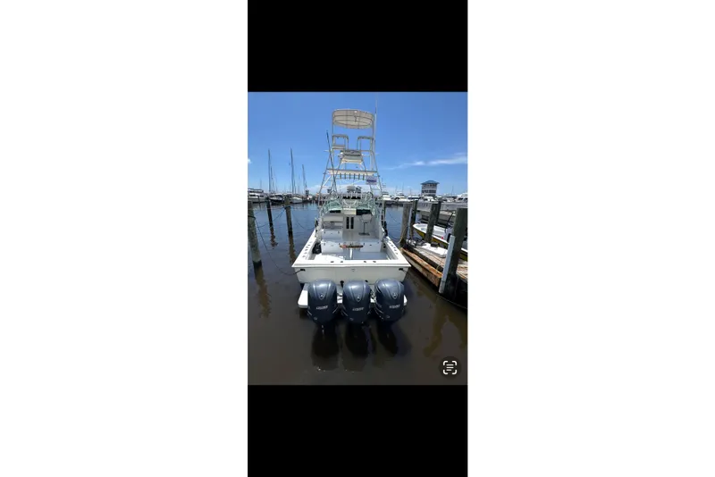 Slide: The Image of 1984 Topaz 37 boat with triple outboard engines docked at a marina. - 2