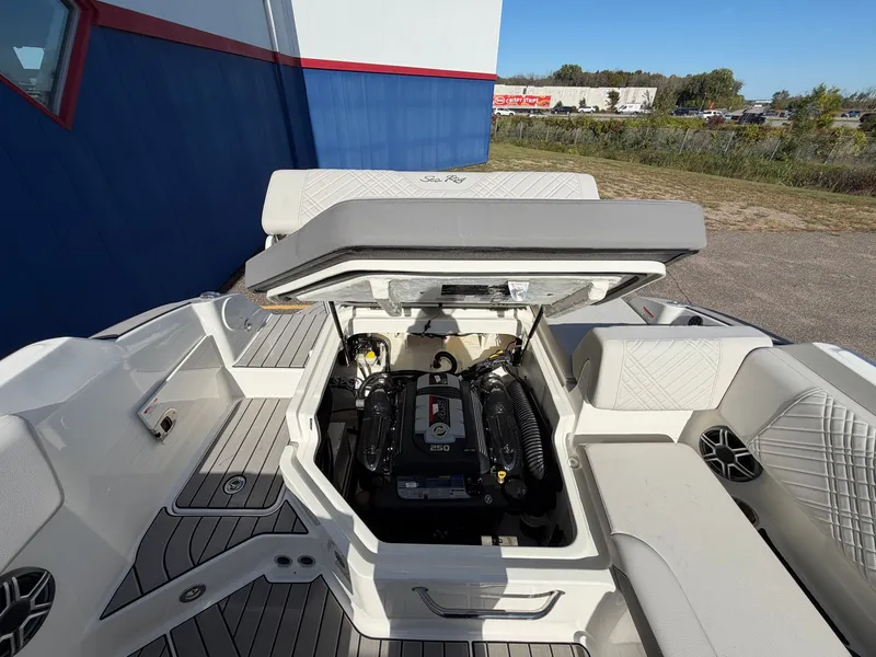 Slide: The Image of The image shows the engine compartment of a 2026 Sea Ray SDX 230 boat. The engine is visible, surrounded by cushioned seating and a modern deck design. - 42