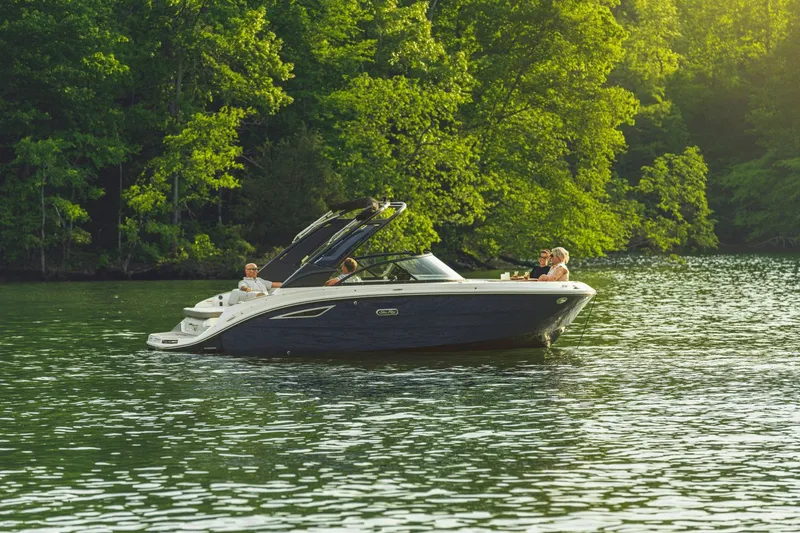Slide: The Image of A 2026 Sea Ray SDX 230 cruising on a calm lake, surrounded by lush greenery. - 10