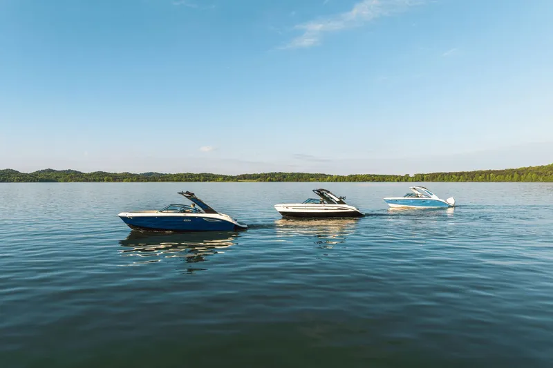 Slide: The Image of Three modern boats cruise on a calm lake, surrounded by wooded hills under a blue sky. - 27