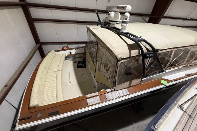 Slide: The Image of 1979 Magnum 38 Sport boat in storage, featuring beige seating and a covered cockpit. - 12
