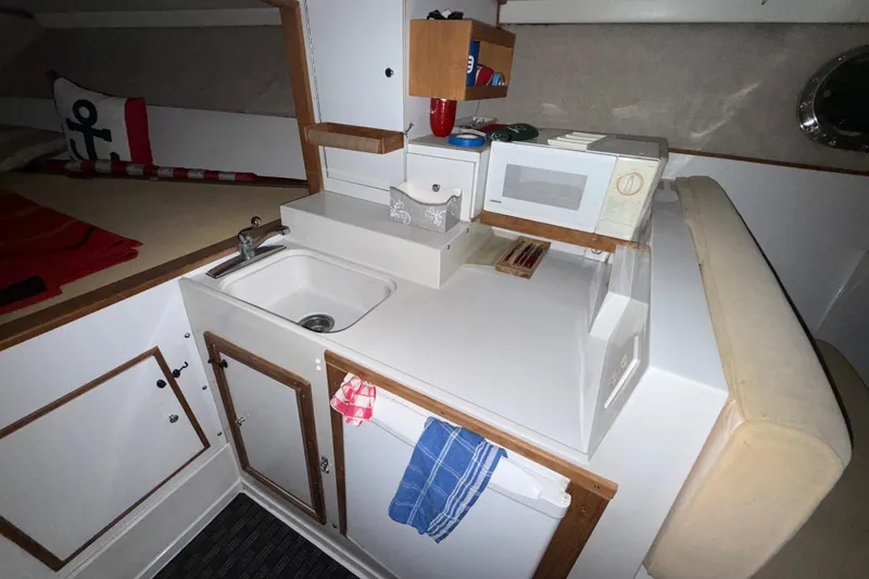 Slide: The Image of Compact kitchen area in a 1979 Magnum 38 Sport boat, featuring a sink and microwave. - 42