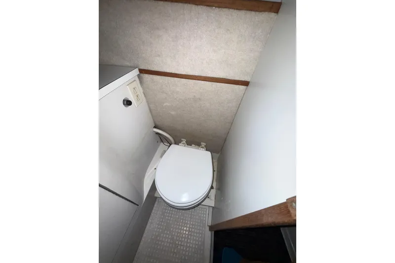 Slide: The Image of Compact bathroom interior of a 1979 Magnum 38 Sport boat, featuring a white toilet. - 47