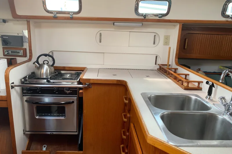 Slide: The Image of 1994 Caliber Cutter Rig yacht kitchen with stove, sink, and wooden cabinetry. - 38