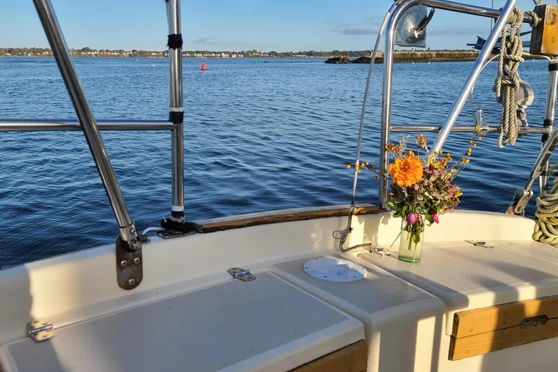 Slide: The Image of Caliber Cutter Rig 1994 sailboat deck with flowers, overlooking calm waters and distant shoreline. - 5