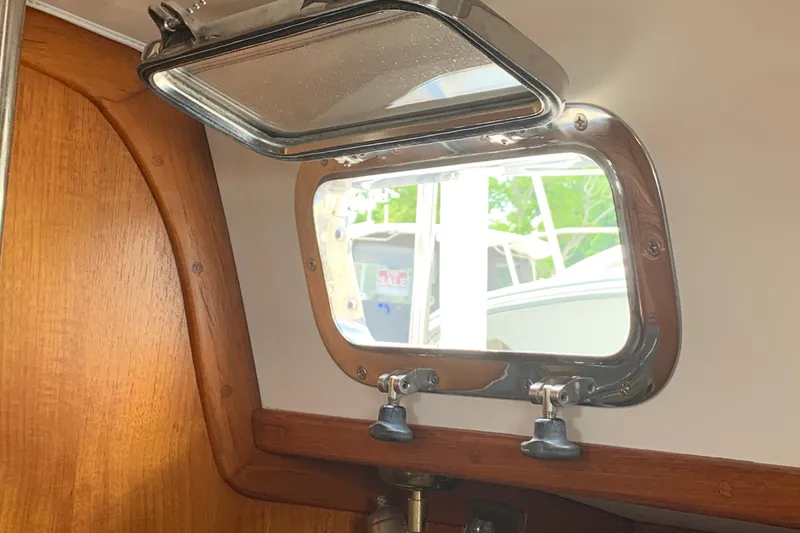 Slide: The Image of Interior view of a 1994 Caliber Cutter Rig sailboat, featuring a polished porthole window. - 52