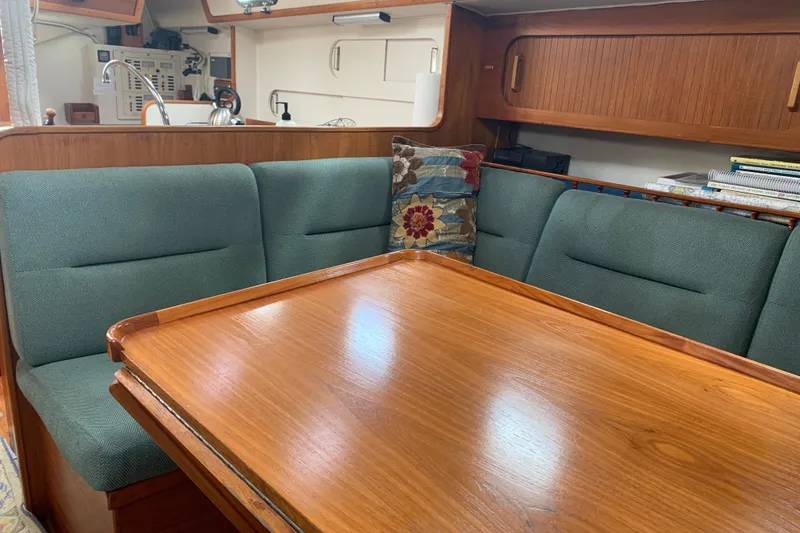 Slide: The Image of Cozy interior of 1994 Caliber Cutter Rig sailboat with wooden table and green seating. - 56
