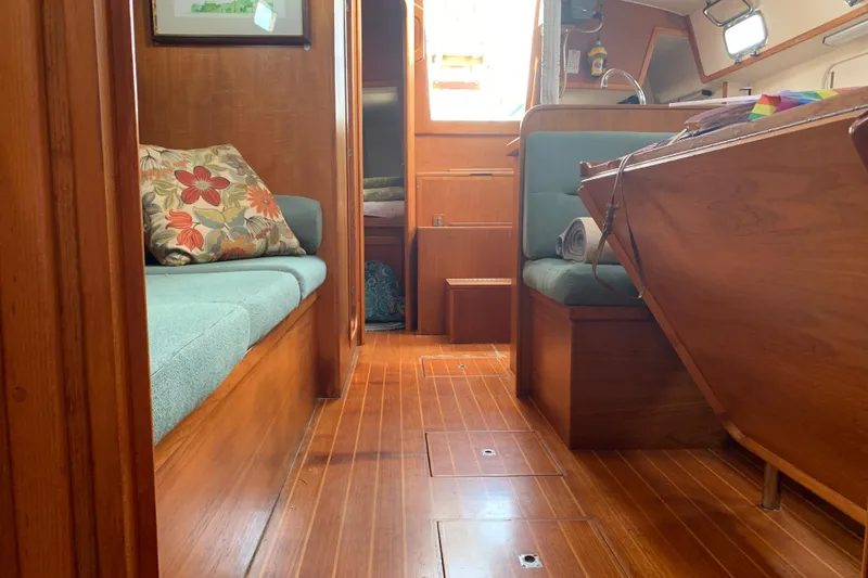 Slide: The Image of Interior of a 1994 Caliber Cutter Rig sailboat with wooden flooring and cozy seating. - 63