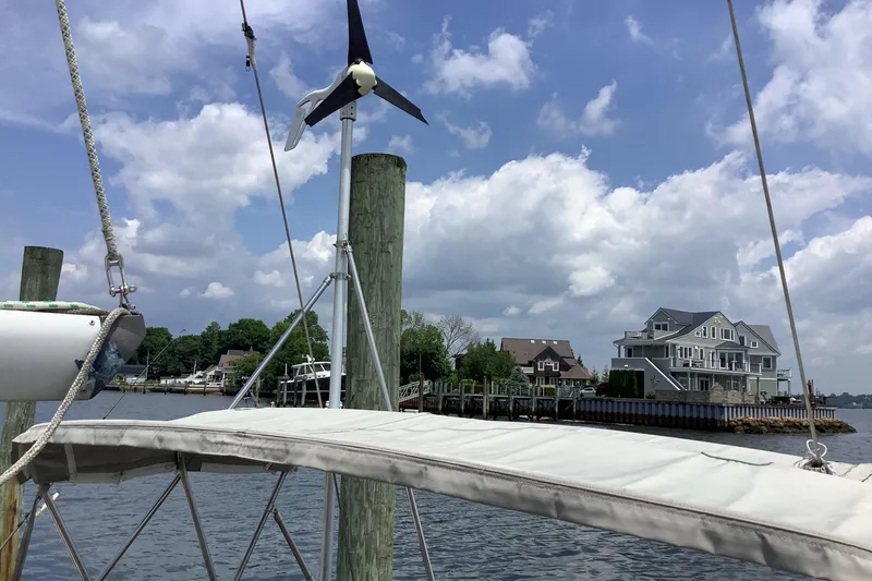 Slide: The Image of Sailboat docked near waterfront homes, featuring a wind turbine, under a partly cloudy sky. - 7