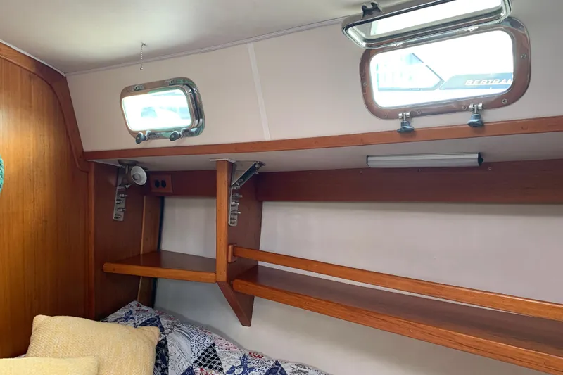 Slide: The Image of Interior of a 1994 Caliber Cutter Rig sailboat with wooden shelves and portholes. - 73