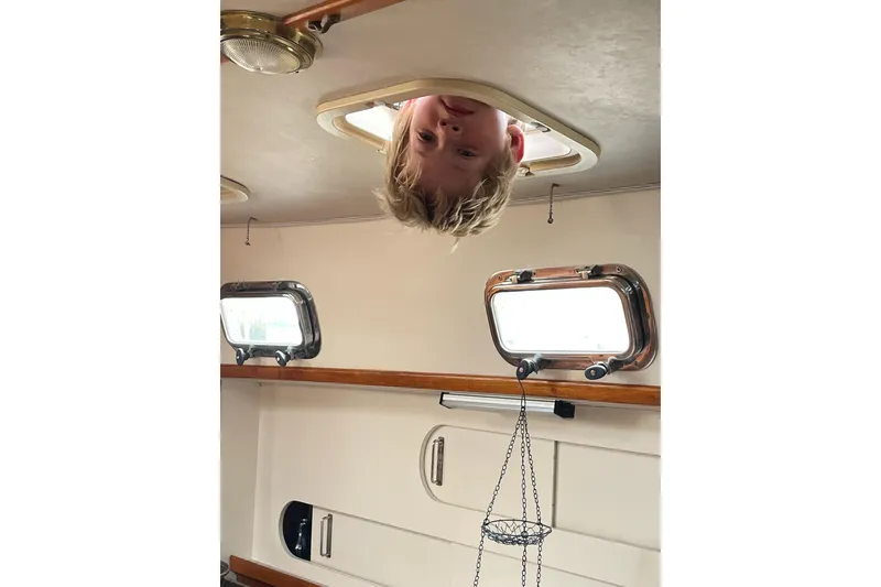 Slide: The Image of Child peeking through hatch on 1994 Caliber Cutter Rig sailboat interior. - 82