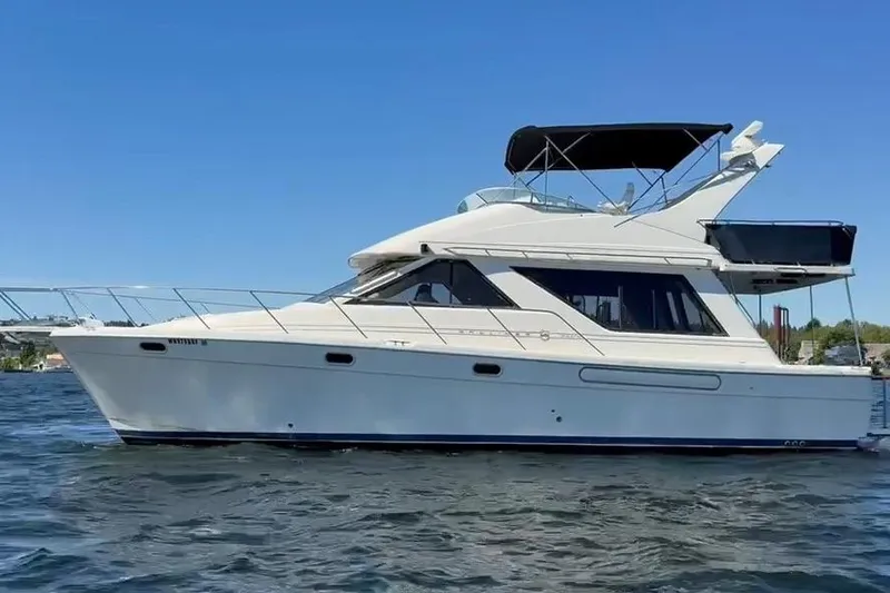 The Image of 1997 Bayliner 3988 Command Bridge Motoryacht on calm water under clear blue sky. - 0