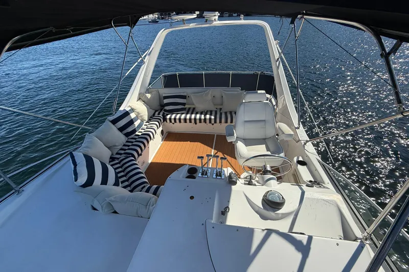 Slide: The Image of 1997 Bayliner 3988 Command Bridge Motoryacht with striped seating, overlooking sparkling water. - 10