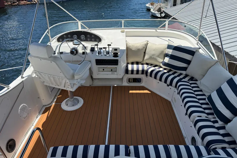 Slide: The Image of 1997 Bayliner 3988 Command Bridge Motoryacht with striped seating and helm, docked by the water. - 7