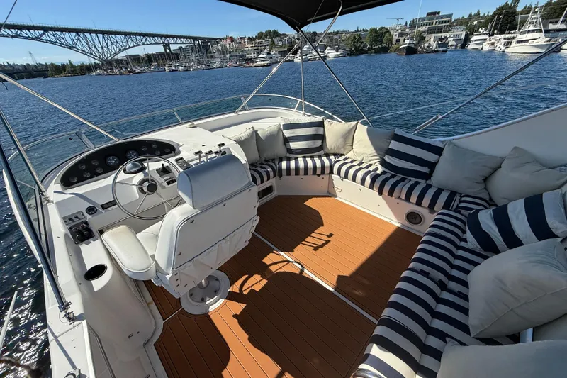 Slide: The Image of 1997 Bayliner 3988 Command Bridge Motoryacht with striped seating, overlooking marina and bridge. - 9