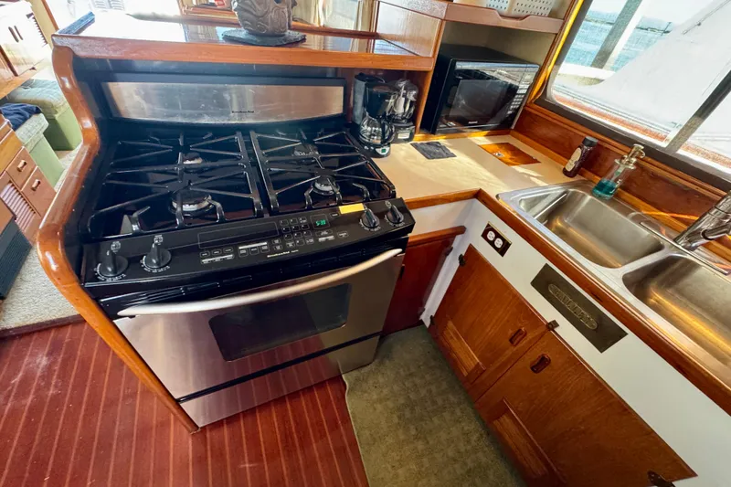 Slide: The Image of 1958 Blanchard Pilothouse kitchen with stove, sink, and wooden cabinetry. - 21
