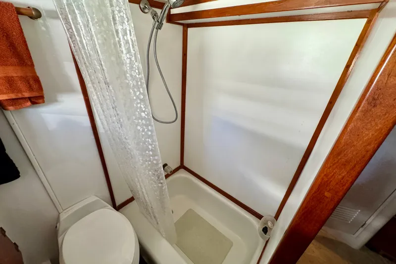 Slide: The Image of 1958 Blanchard Pilothouse bathroom with shower, wooden trim, and orange towel. - 37
