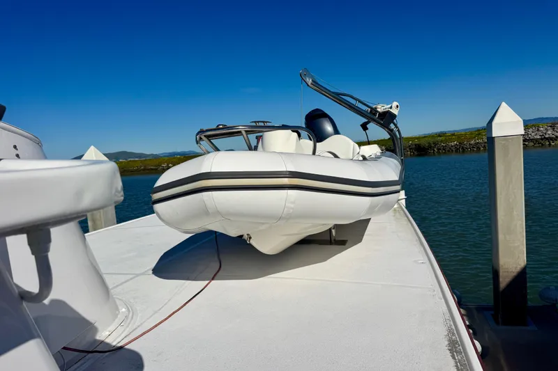 Slide: The Image of 1958 Blanchard Pilothouse boat with inflatable dinghy on deck, docked by calm waters. - 48