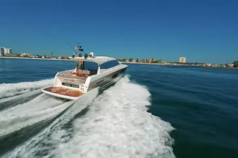 Slide: The Image of 2013 Prestige 550 S yacht cruising on open water, cityscape in background. - 5