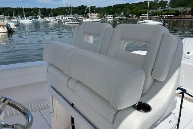 Slide: The Image of 2022 Intrepid 327 Center Console boat with white seating, docked in a marina. - 10