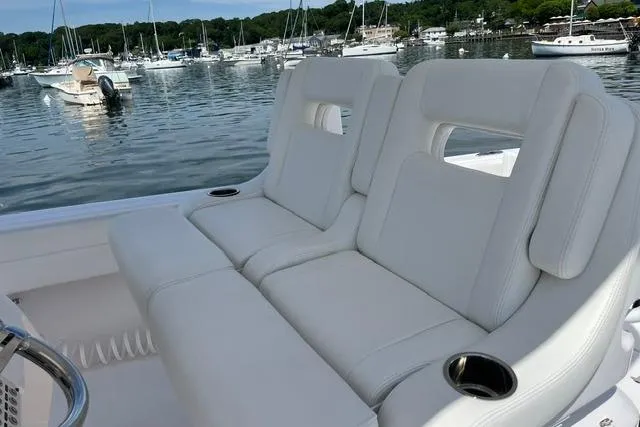 Slide: The Image of 2022 Intrepid 327 Center Console boat with white cushioned seating, docked in a marina. - 11