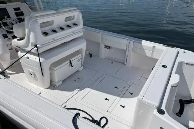 Slide: The Image of 2022 Intrepid 327 Center Console boat interior with seating and storage, docked on calm water. - 2