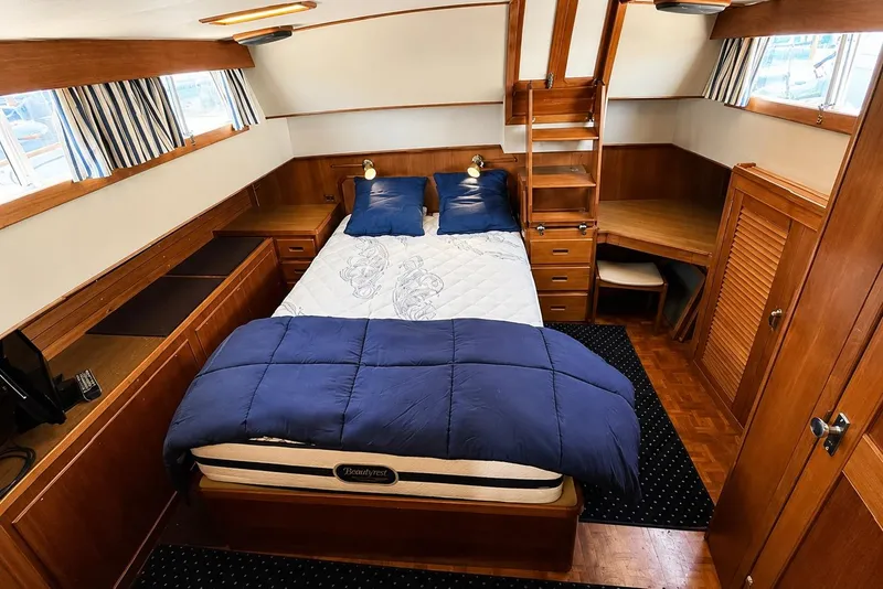 Slide: The Image of Luxurious 1989 Grand Banks 42 Classic yacht bedroom with wood furnishings and cozy bedding. - 32