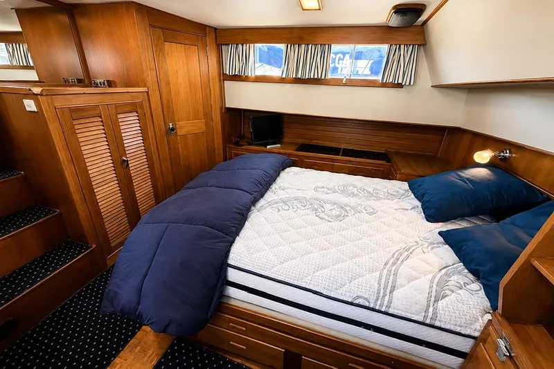 Slide: The Image of Cozy bedroom in 1989 Grand Banks 42 Classic yacht with wood paneling and blue bedding. - 33