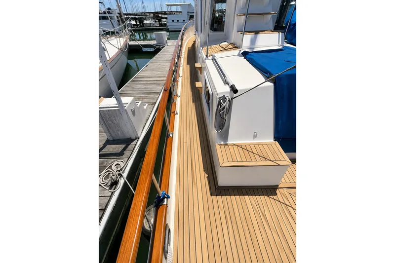 Slide: The Image of Deck view of 1989 Grand Banks 42 Classic yacht, featuring teak wood and marina setting. - 11