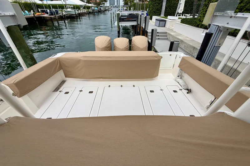 Slide: The Image of 2018 Pursuit S 408 Sport boat deck with beige seating covers, docked by the water. - 11