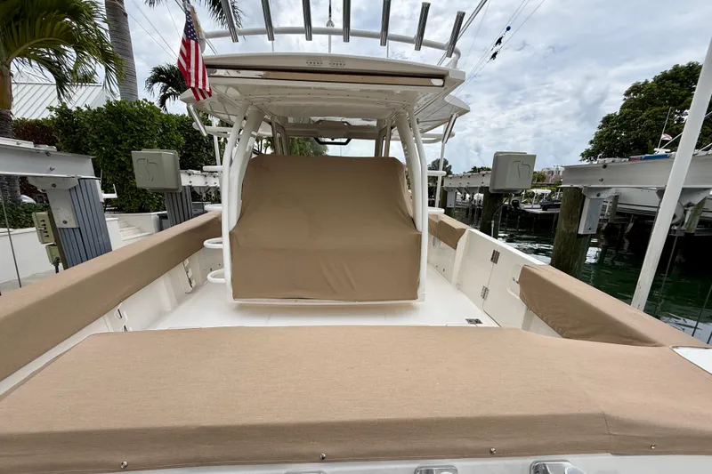 Slide: The Image of 2018 Pursuit S 408 Sport boat docked, featuring beige seating and covered helm. - 12