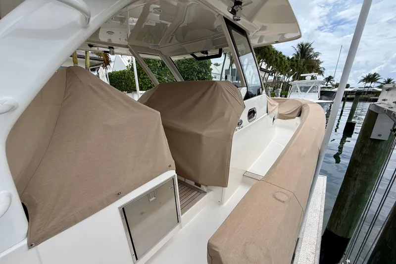 Slide: The Image of 2018 Pursuit S 408 Sport boat with covered seating, docked by palm trees. - 14