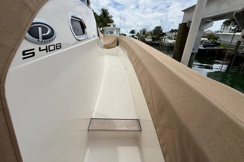 Slide: The Image of 2018 Pursuit S 408 Sport boat docked, featuring sleek design and beige covers. - 15