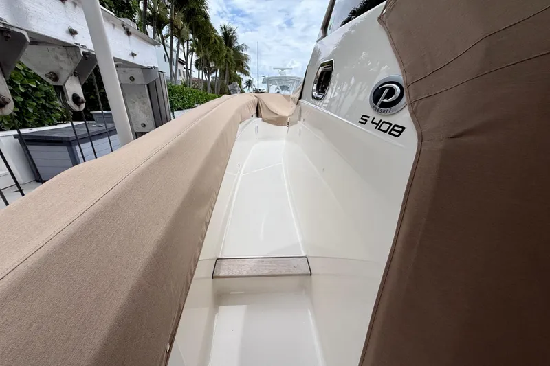 Slide: The Image of 2018 Pursuit S 408 Sport boat with protective cover, docked near palm trees. - 16