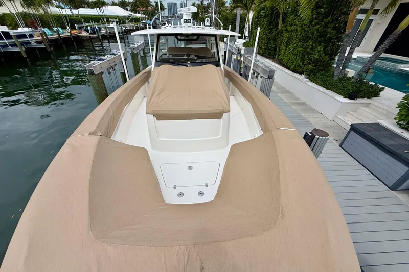 Slide: The Image of 2018 Pursuit S 408 Sport boat docked, covered in tan canvas, surrounded by water and greenery. - 19