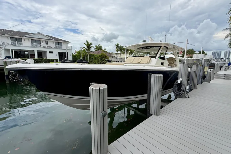 Slide: The Image of 2018 Pursuit S 408 Sport boat docked by waterfront home under cloudy sky. - 23