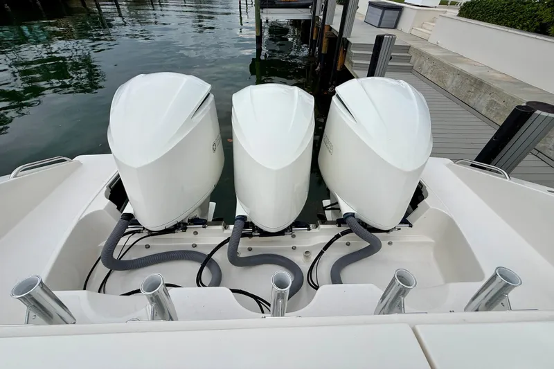 Slide: The Image of Triple outboard engines on a 2018 Pursuit S 408 Sport boat docked by the water. - 26