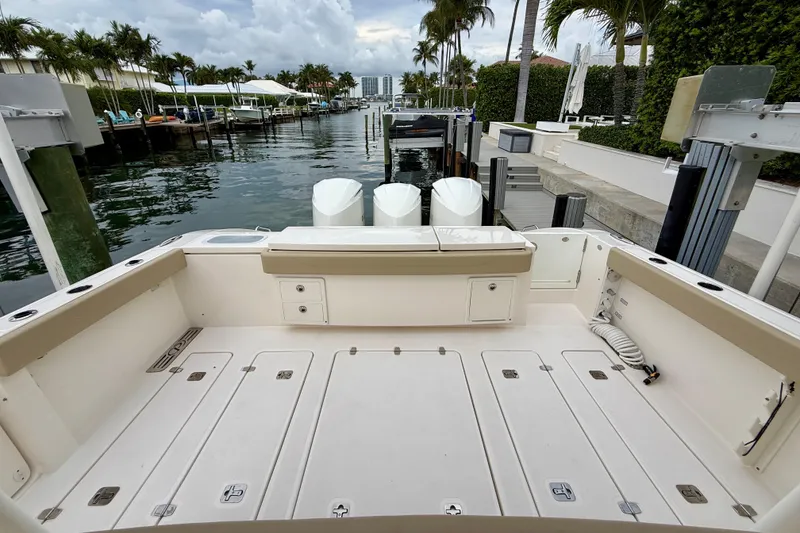 Slide: The Image of 2018 Pursuit S 408 Sport boat docked, featuring spacious deck and triple outboard engines. - 27