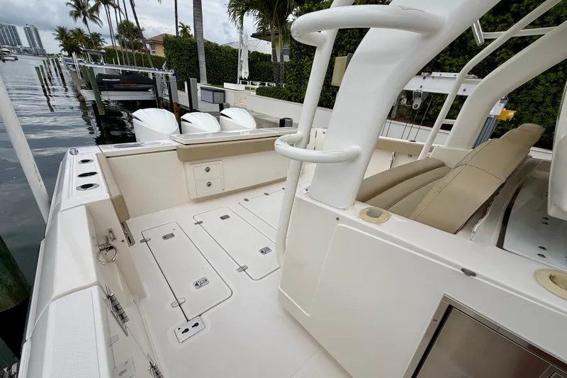 Slide: The Image of 2018 Pursuit S 408 Sport boat interior with seating and storage, docked by palm trees. - 29