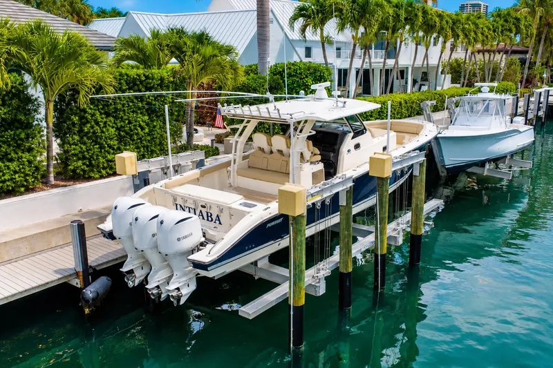 Slide: The Image of 2018 Pursuit S 408 Sport boat docked with triple Yamaha engines, surrounded by lush greenery. - 3