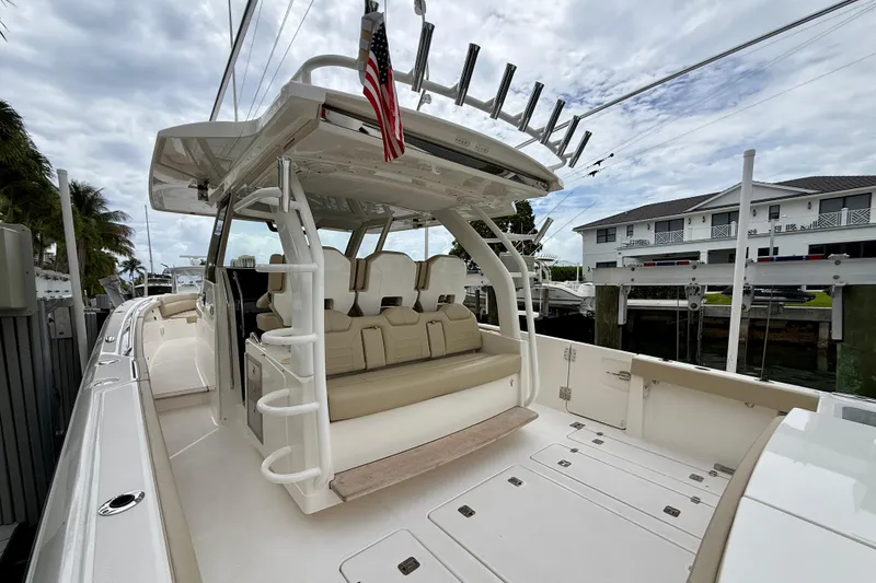 Slide: The Image of 2018 Pursuit S 408 Sport boat with spacious seating and rod holders, docked near waterfront homes. - 31