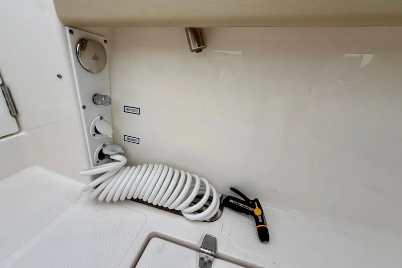 Slide: The Image of 2018 Pursuit S 408 Sport boat deck with coiled hose and water controls. - 38