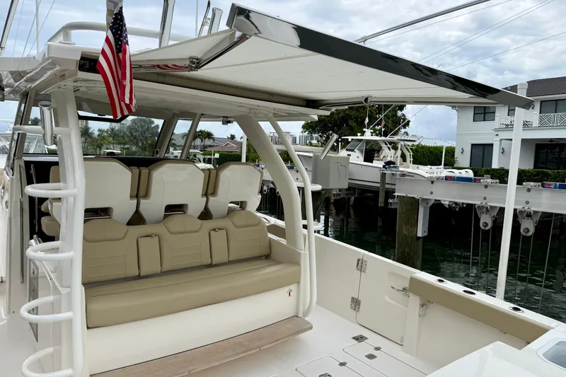 Slide: The Image of 2018 Pursuit S 408 Sport boat with seating and canopy, docked near waterfront homes. - 44