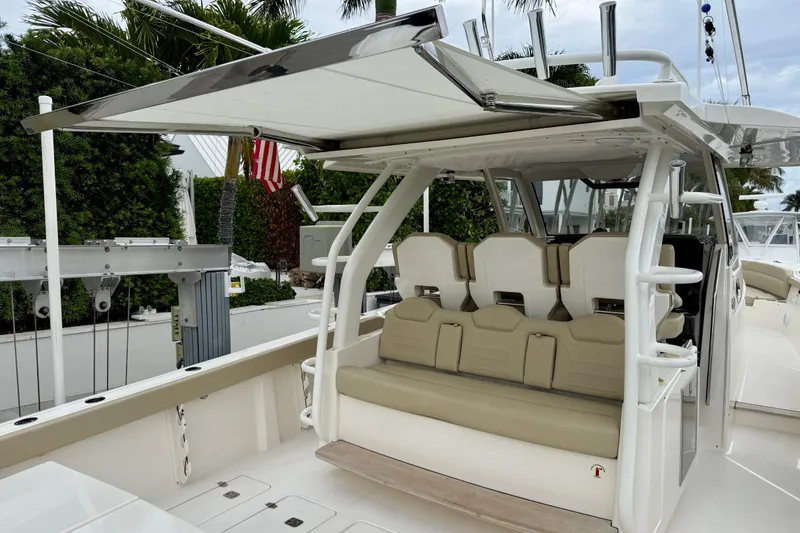 Slide: The Image of 2018 Pursuit S 408 Sport boat with seating and canopy, docked near lush greenery. - 45